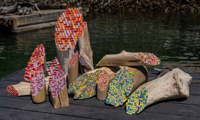 Painted salvaged wood sculptures by Jos Prol on a dock beside the Gowanus Canal