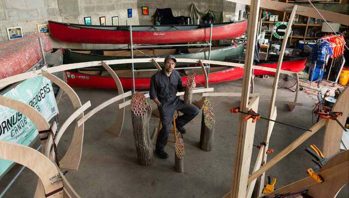 Jos Prol seated among his painted wood sculptures in his Gowanus boathouse studio, 2024 to 2025